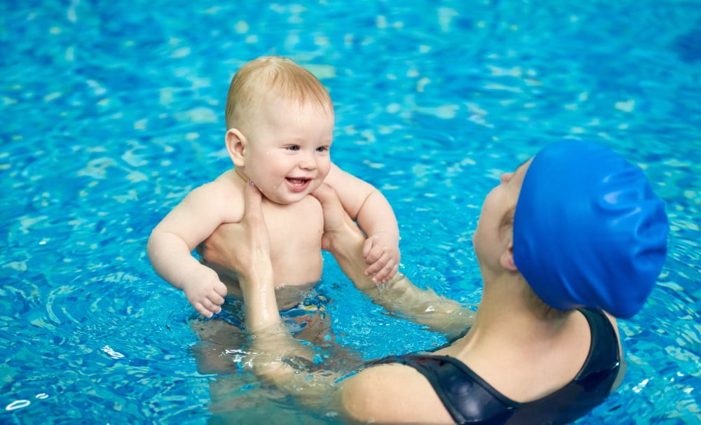 Baby i svømmehal med sin mor